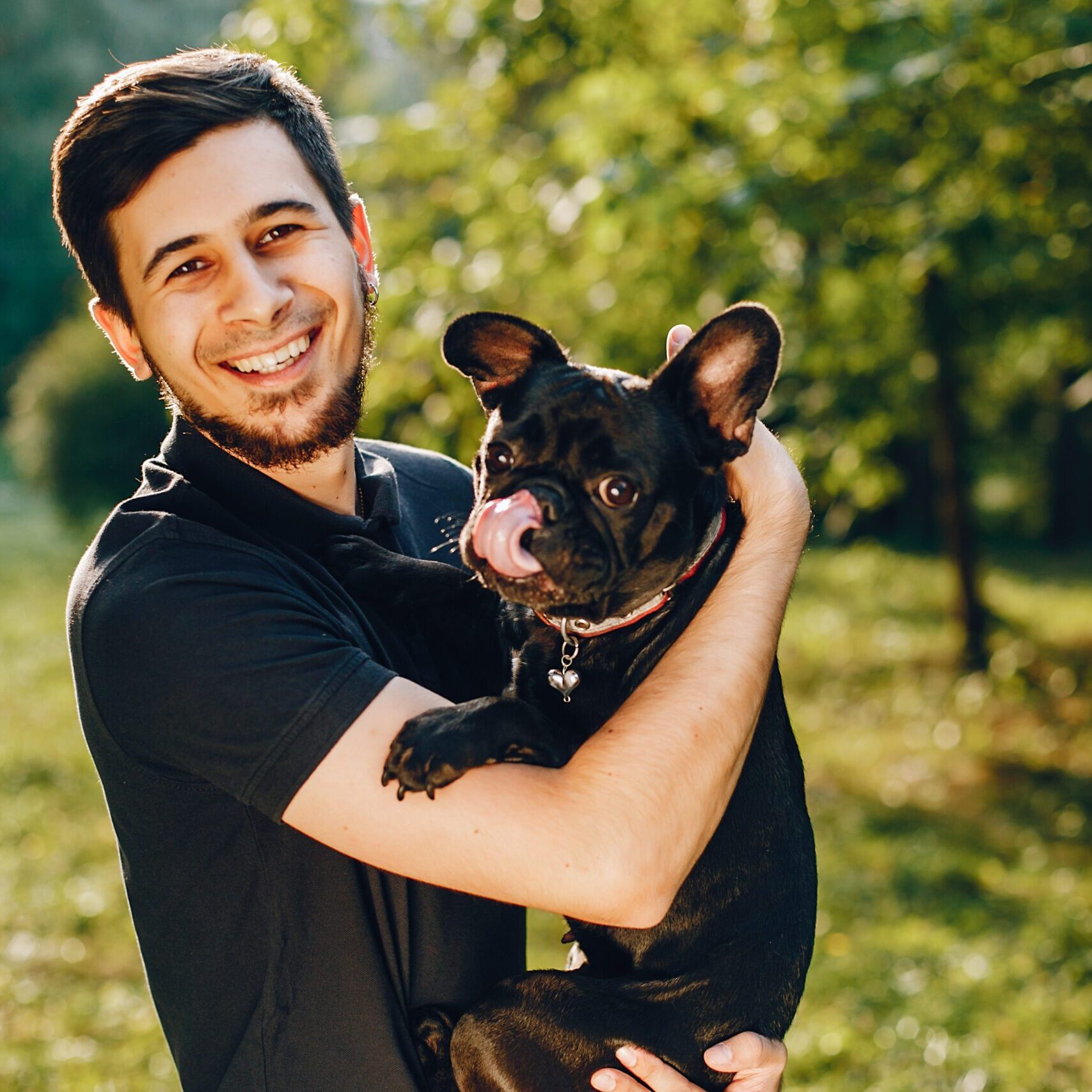 Handsome man standing in a summer park. Guy with dog.